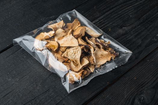 Dried mushrooms set, on black wooden table background, in plastic pack