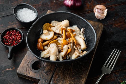 Marinated mushrooms set, on old dark wooden table background