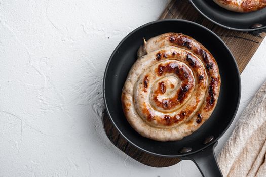 Grilled Spiral sausage set in cast iron frying pan, on white background, top view flat lay , with space for text copyspace