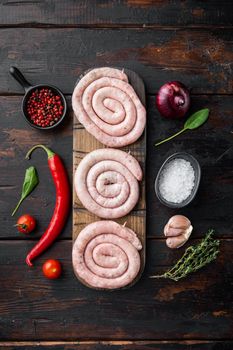 Raw snail sausage in traditional spiral set, on old dark wooden table background, top view flat lay