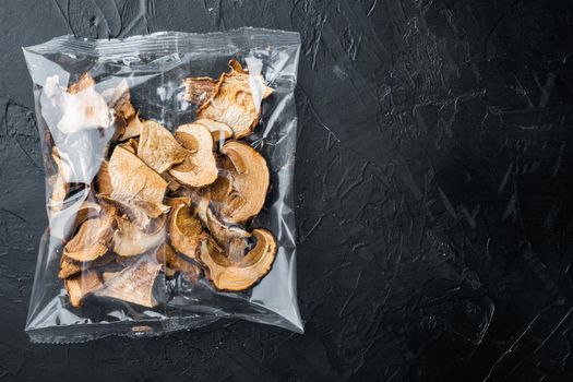 Dried mushrooms set, on black background, in plastic pack, top view flat lay , with space for text copyspace