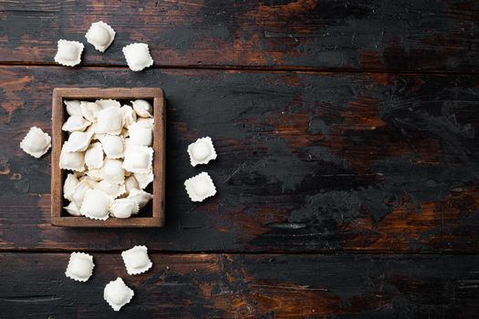 Frozen ravioli set in wooden box on old dark wooden table background, top view flat lay , with copyspace and space for text