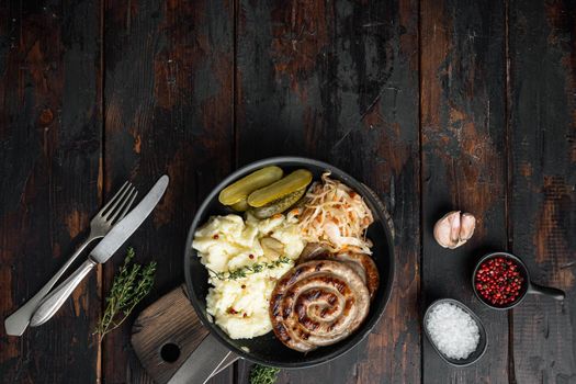 Bavarian fried sausage on sauerkraut in cast iron frying pan, on old dark wooden table background, top view flat lay , with space for text copyspace