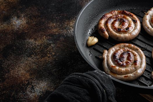 Grilled pork meat sausages set in cast iron frying pan, on old dark rustic background , with space for text copyspace