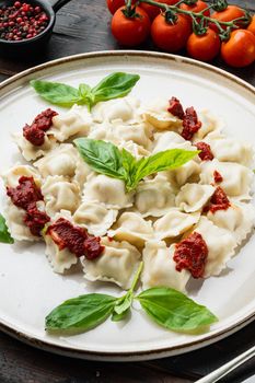 Ravioli pasta with mushroom cream sauce and cheese - Italian food style set with basil parmesan and tomatoe on white plate on old dark wooden table background