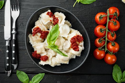 Ravioli pasta with mushroom cream sauce and cheese - Italian food style set with basil parmesan and tomatoe in black bowl, on black wooden table background, top view flat lay