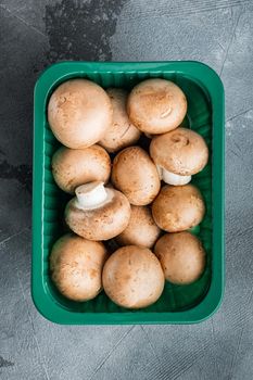 Brown champignons mushroom set, on gray background, in plastic pack, top view flat lay