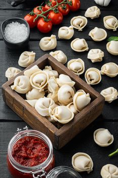 Tortellini ingredients set, on black wooden table background