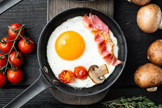 Fried Egg with ingredient in cast iron frying pan, on black wooden table background, top view flat lay