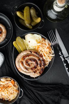Roasted sausages with fermented cabbages, on black background, top view flat lay