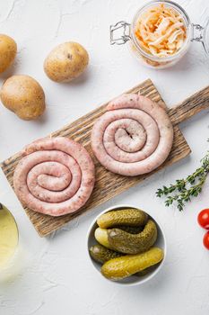 Wurst or Bratwurst with Fermented Cabbage, Pickled Cucumber, and Spices, on white background, top view flat lay