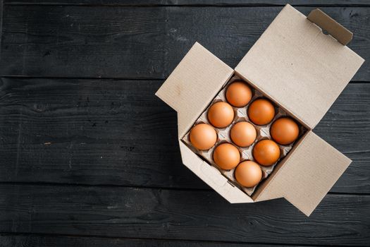 Chicken eggs in an egg box tray set, on black wooden table background, top view flat lay , with space for text copyspace