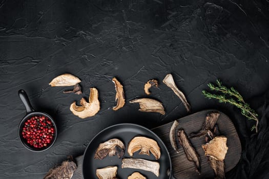 Dried wild mushrooms set in cast iron frying pan, on black background, top view flat lay , with space for text copyspace