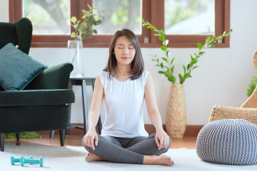 Beautiful asian woman keep calm and meditates while practicing yoga at home for healthy trend lifestyle