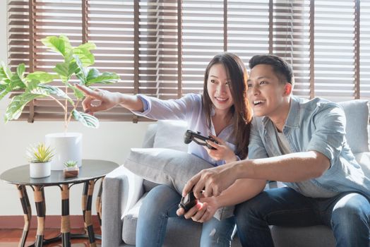 Asian couple lovers enjoy and play console game on vacation make more quality time of happiness together at home