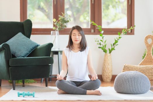 Beautiful asian woman keep calm and meditates while practicing yoga at home for healthy trend lifestyle
