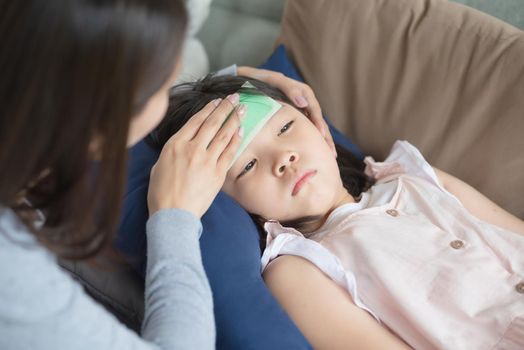 Asian mother take care of her kid which got fever and illness at home.