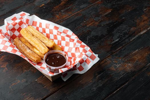 Churros with sugar powder, in the box in paper tray, on old dark wooden table background with space for text, copyspace