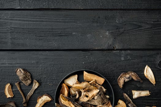Mix of chopped wild dried mushrooms set, on black wooden table background, top view flat lay , with space for text copyspace