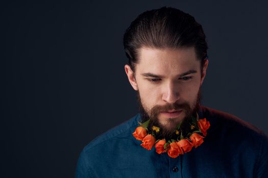 Bearded man flowers in a beard close-up romance dark background. High quality photo