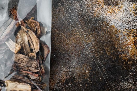 Dried mushrooms set, on old dark rustic background, in plastic pack, top view flat lay , with space for text copyspace