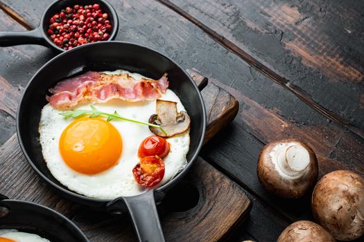 Scrambled eggs in frying pan with pork lard, bread and green feather in cast iron frying pan, on old dark wooden table background , with space for text copyspace