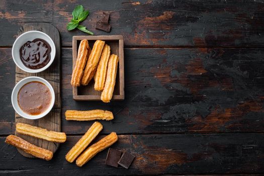 Traditional Spanish dessert churros with sugar and chocolate set, on old dark wooden table background, top view flat lay with space for text, copyspace