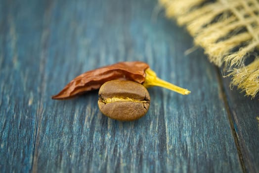 Macro photo of dried red chili pepper and roasted coffee beans on wooden background
