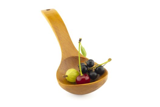 Gooseberries, cherries and black currants in a wooden spoon isolated on a white background