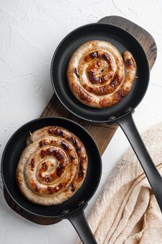Homemade Spiral grilled sausage set in cast iron frying pan, on white background, top view flat lay