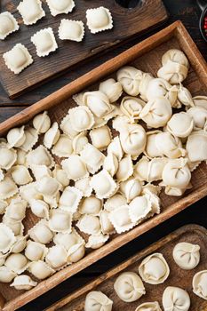 Raw Italian ravioli tortellini with fresh parmesan and basil , tomatoes set on old dark wooden table background, top view flat lay