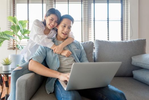 Asian couple lovers enjoy watching online streaming via computer laptop at home