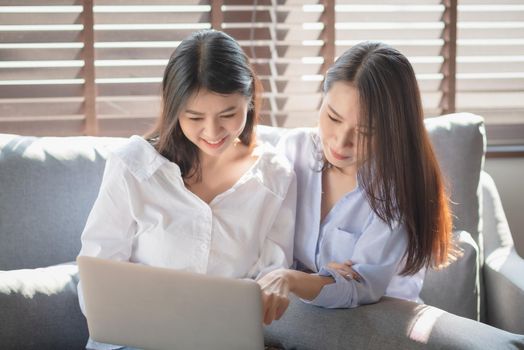 Two young woman use laptop computer to shopping online via internet during stay safe at home