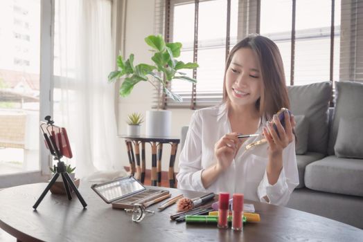 Young female beauty influencer making a video tutorial for her beauty channel on cosmetics during stay safe at home