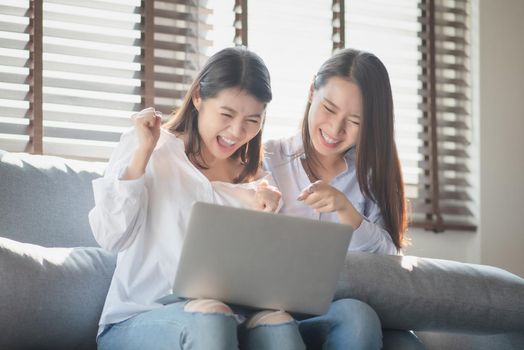 Two young woman use laptop computer to shopping online via internet during stay safe at home