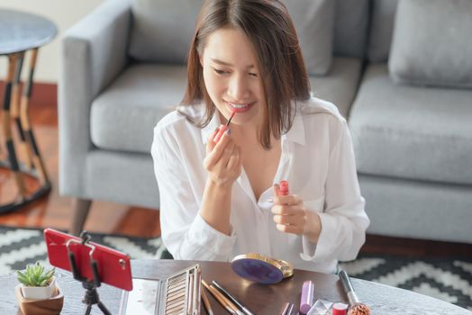 Young female beauty influencer making a video tutorial for her beauty channel on cosmetics during stay safe at home