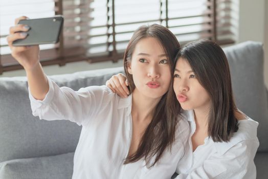 Two young female using mobile phone and internet technology to use video call to other friends during stay safe at home