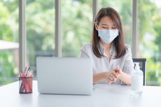 Business woman wearing mask and using personal sanitizer to cleaning her hand in office to keep hygiene.Preventive during the period of epidemic from coronavirus or covid19.