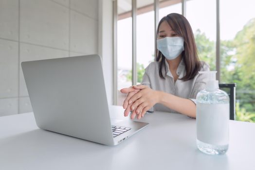 Business woman wearing mask and using personal sanitizer to cleaning her hand in office to keep hygiene.Preventive during the period of epidemic from coronavirus or covid19.
