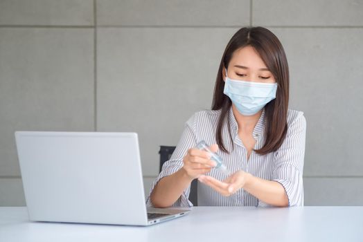 Business woman wearing mask and using personal sanitizer to cleaning her hand in office to keep hygiene.Preventive during the period of epidemic from coronavirus or covid19.