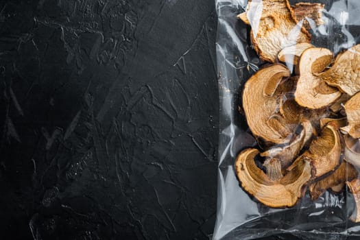 Wild organic dried porcini mushroom set, on black background, in plastic pack, top view flat lay , with space for text copyspace