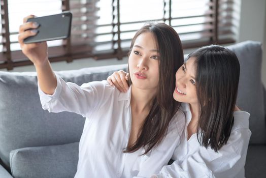Two asian female using mobile phone and internet technology to use video call to other friends during stay safe at home
