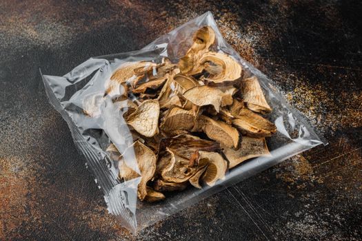 Set of dried mushrooms set, on old dark rustic background, in plastic pack