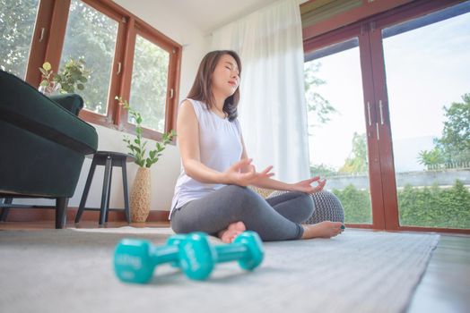 Beautiful asian woman keep calm and meditates while practicing yoga at home for healthy trend lifestyle