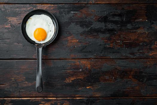Fried eggs with bacon and vegetables set in cast iron frying pan, on old dark wooden table background, top view flat lay , with space for text copyspace