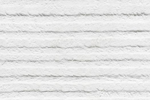 The wall is white with horizontal depressions and roughness on the surface.Texture or background