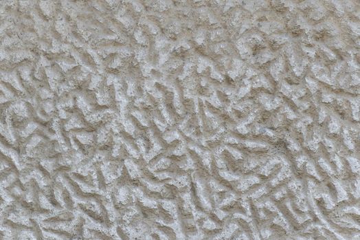 Close-up of a solid wall of rough gray cement with uneven depressions.Texture or background