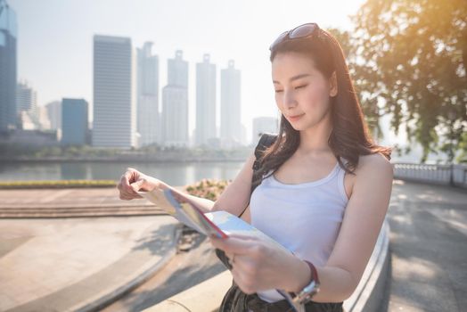 Beautiful asian solo tourist woman  looking at the map searching for tourists sightseeing spot. Vacation travel in summer.