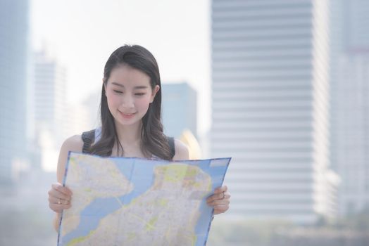 Beautiful asian solo tourist woman looking at the map searching for tourists sightseeing spot. Vacation travel in summer.