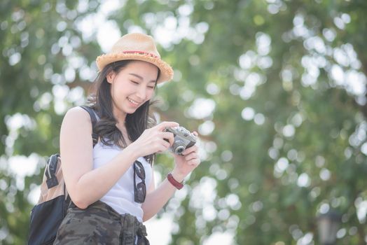 Beautiful asian solo tourist woman enjoy taking photo by retro camera at tourist sightseeing spot. Vacation travel in summer.